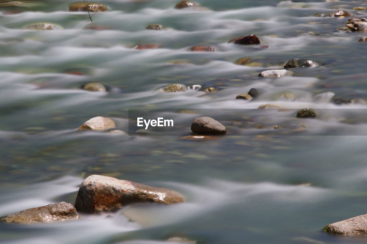 Stones surrounded by passer river in merano, italy