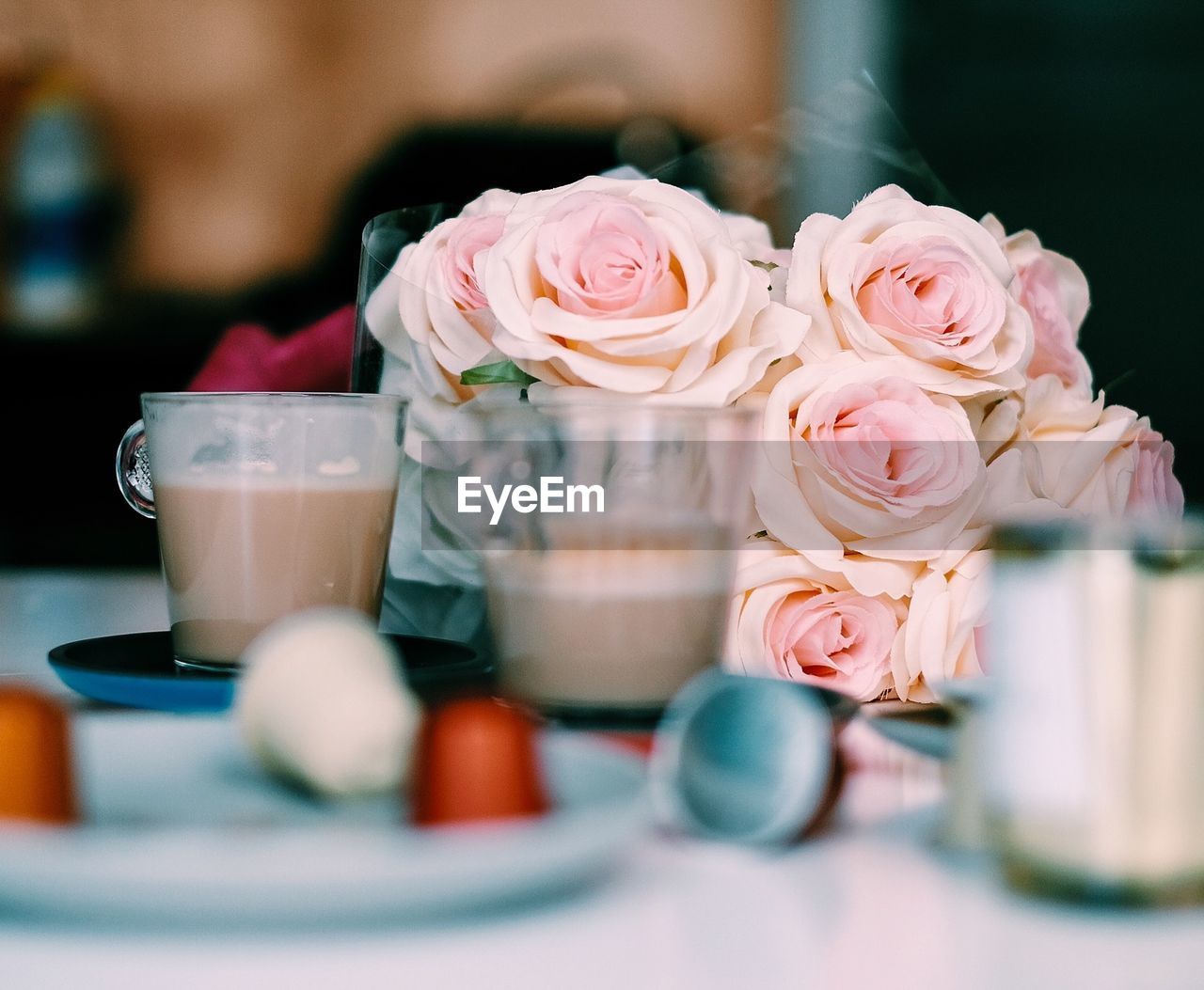 Coffee cups with rose bouquet on table at restaurant