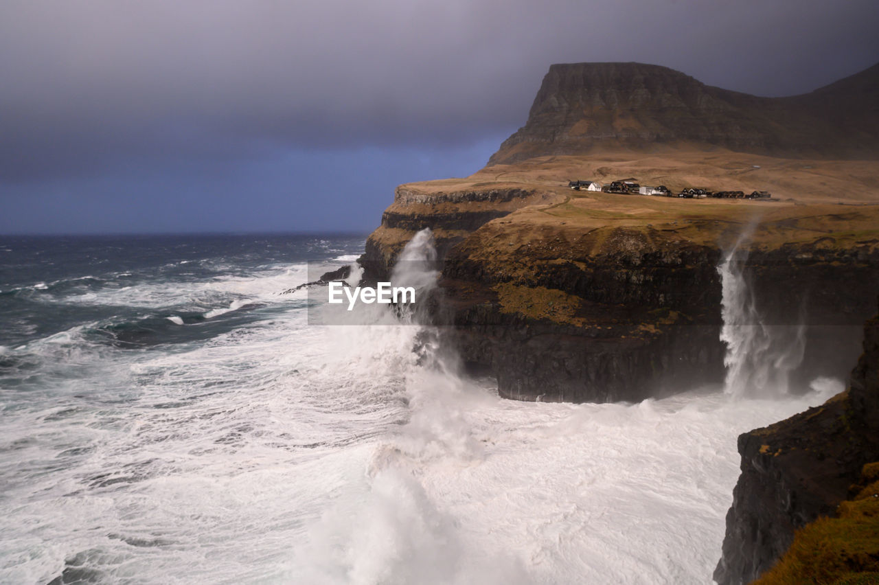 Scenic view of  gitated sea against cliffs. féroé islands landmark.
