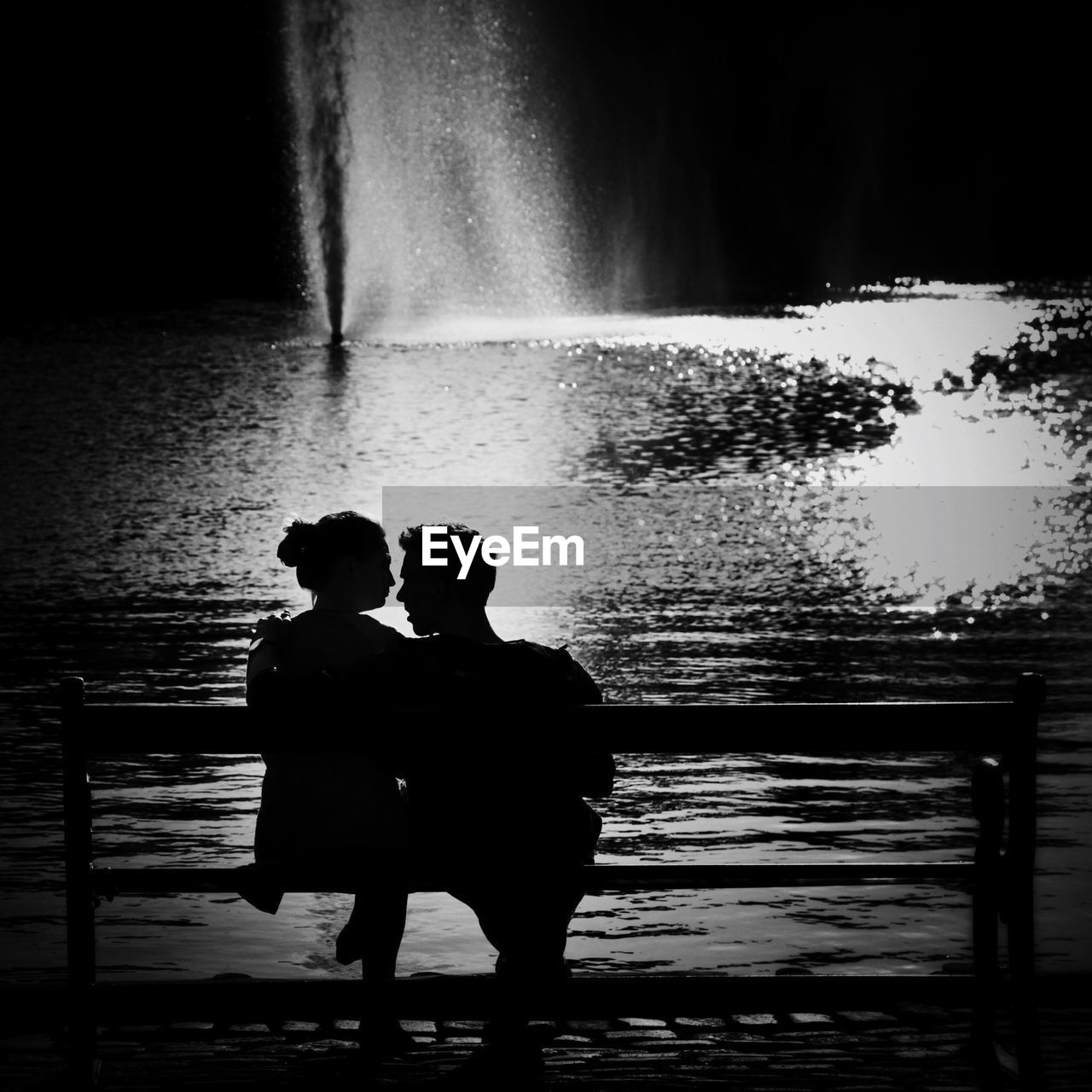 Black and white image of a couple relaxing on a bench