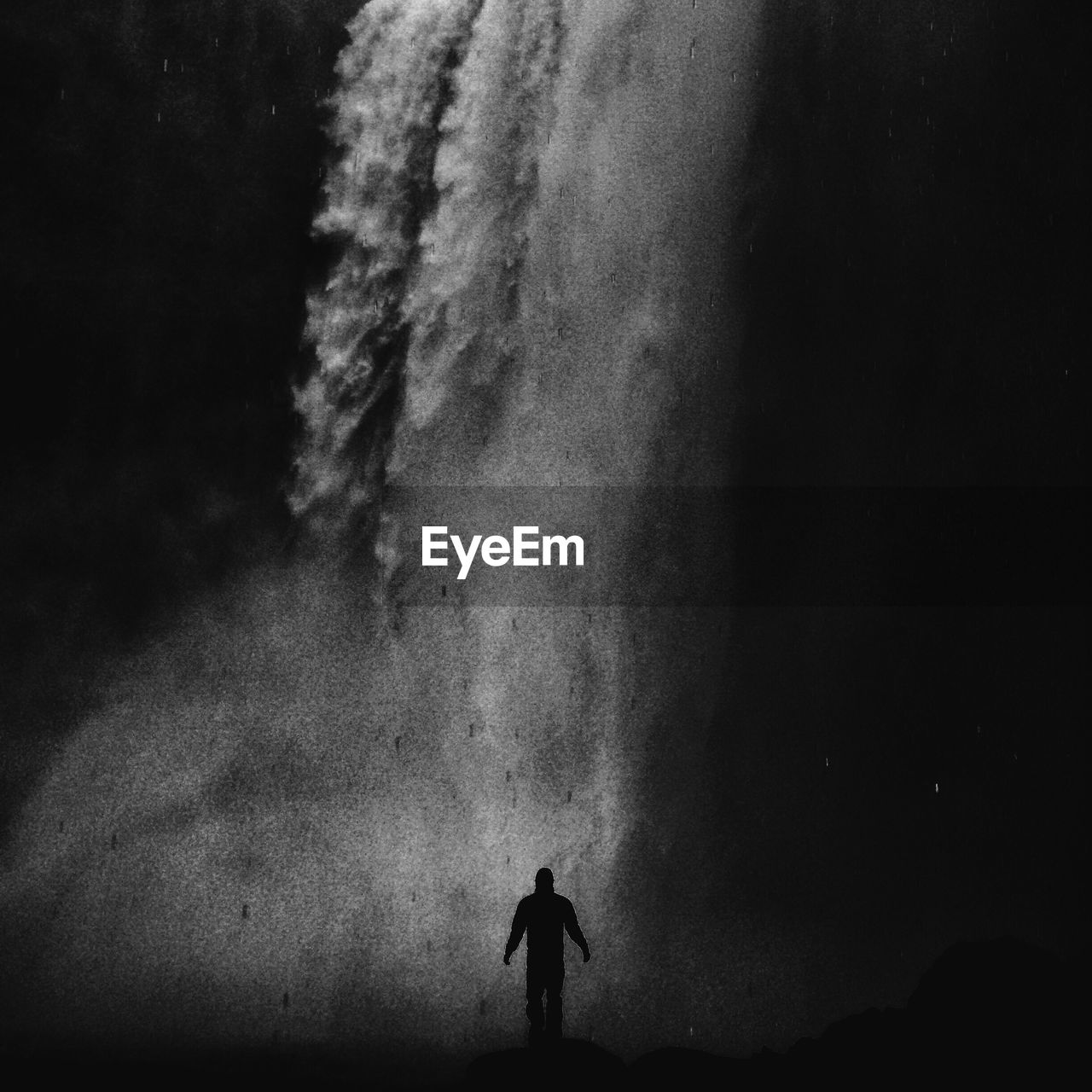 Silhouette man standing against waterfall