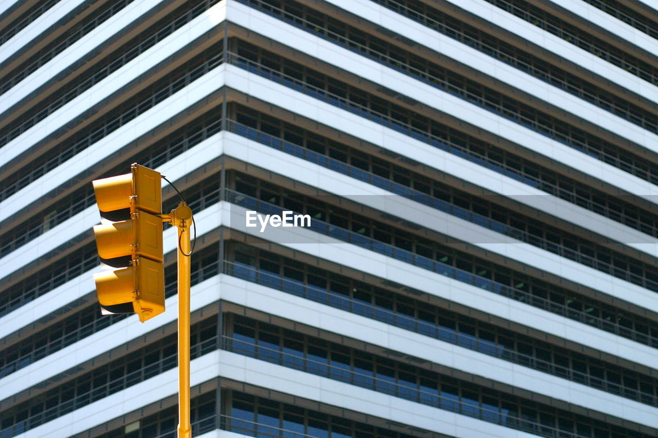 Low angle view of road signal against modern building in city