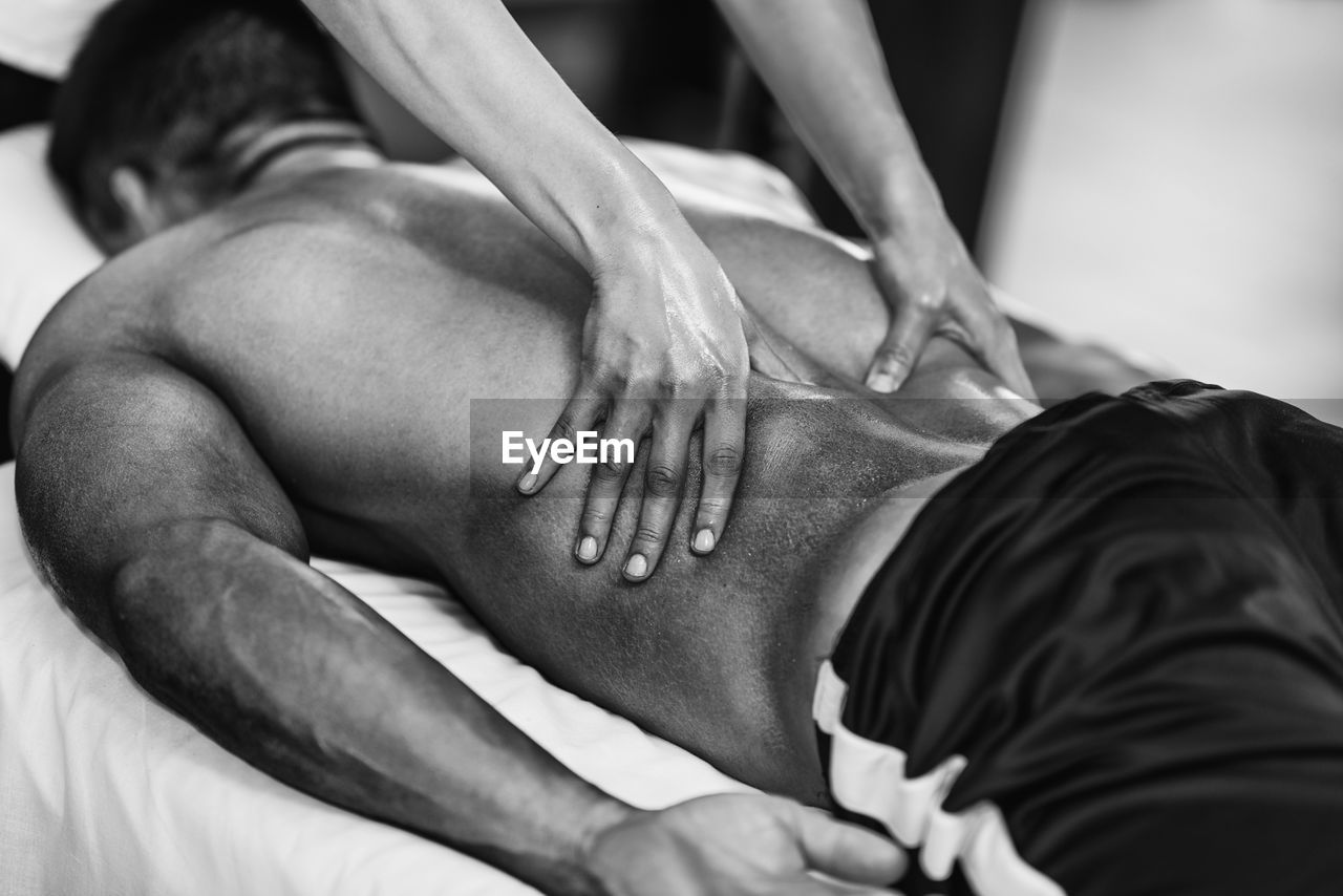 Woman massaging man lying on bed