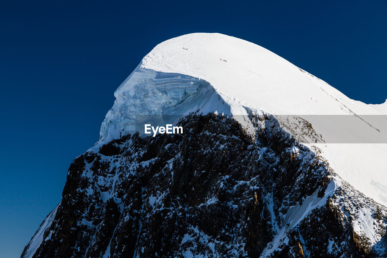 Low angle view of snowcapped mountain against clear blue sky. view from klein matterhorn, swiss alps