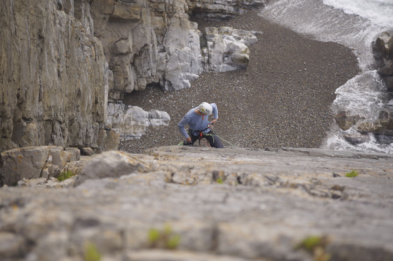 REAR VIEW OF WOMAN WALKING ON ROCK