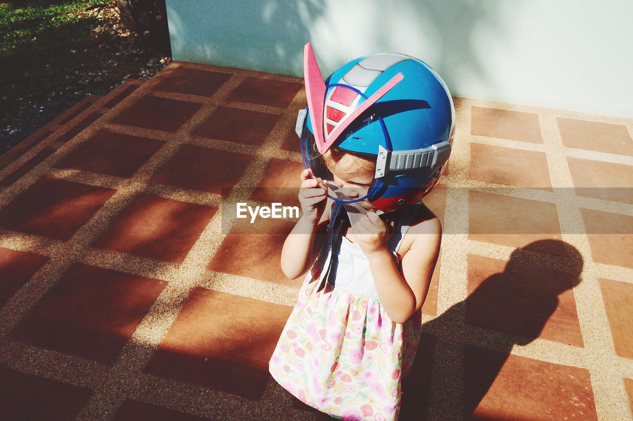 Close-up of cute girl wearing helmet while standing at yard