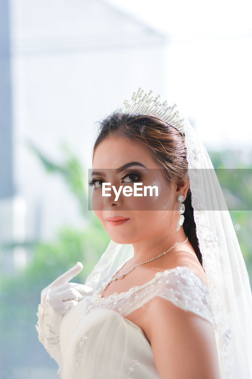 Side view portrait of smiling beautiful bride wearing tiara and wedding dress