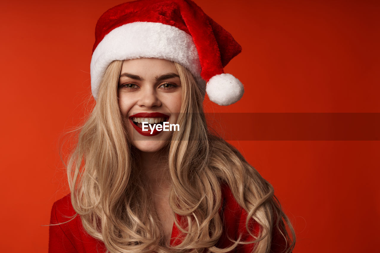 portrait of young woman wearing santa hat against red background