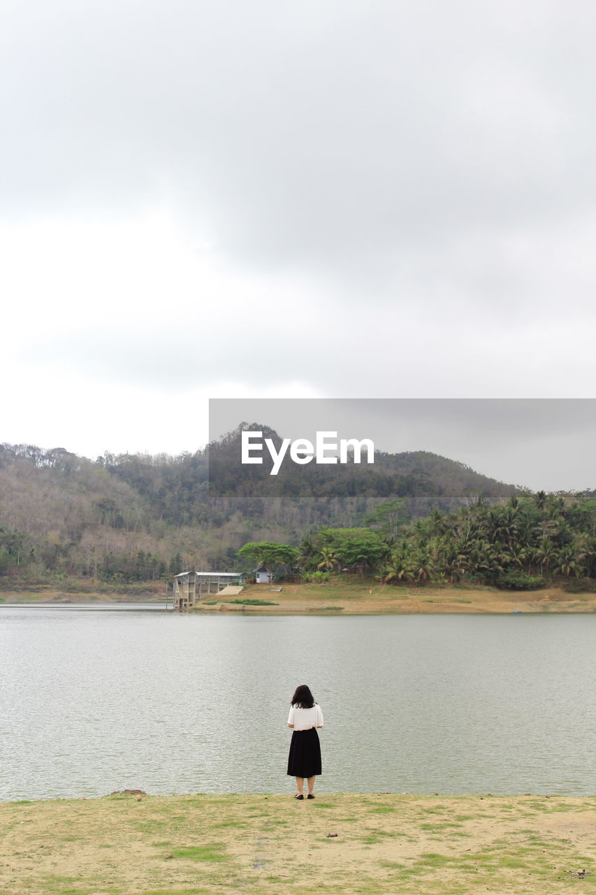 WOMAN LOOKING AT LAKE AGAINST SKY