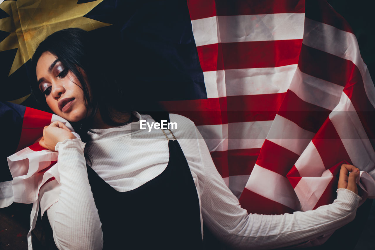 Thoughtful female model posing with malaysian flag on spool