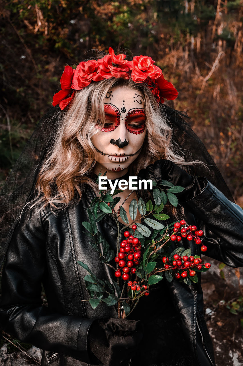 Closeup portrait of calavera catrina. young woman with sugar skull makeup and red flowers. dia