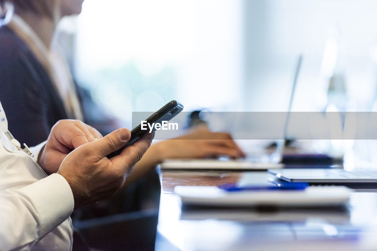 Midsection of man using mobile phone on table