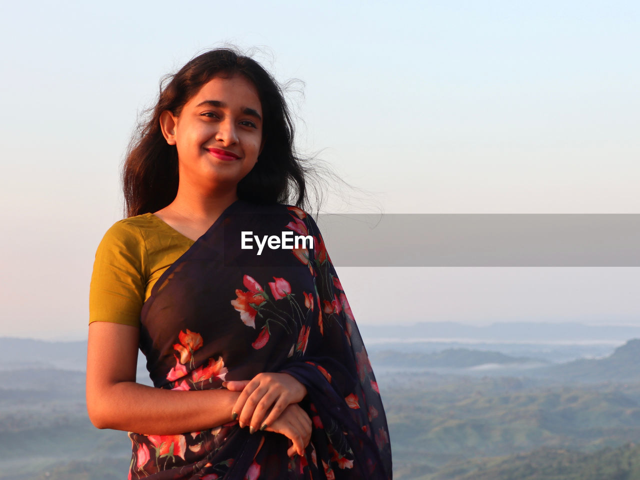 Portrait of young woman standing against sky