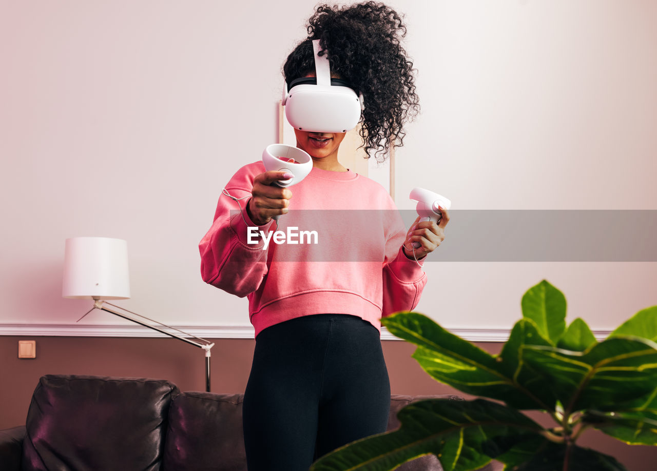 Midsection of woman wearing virtaul reality headset at home