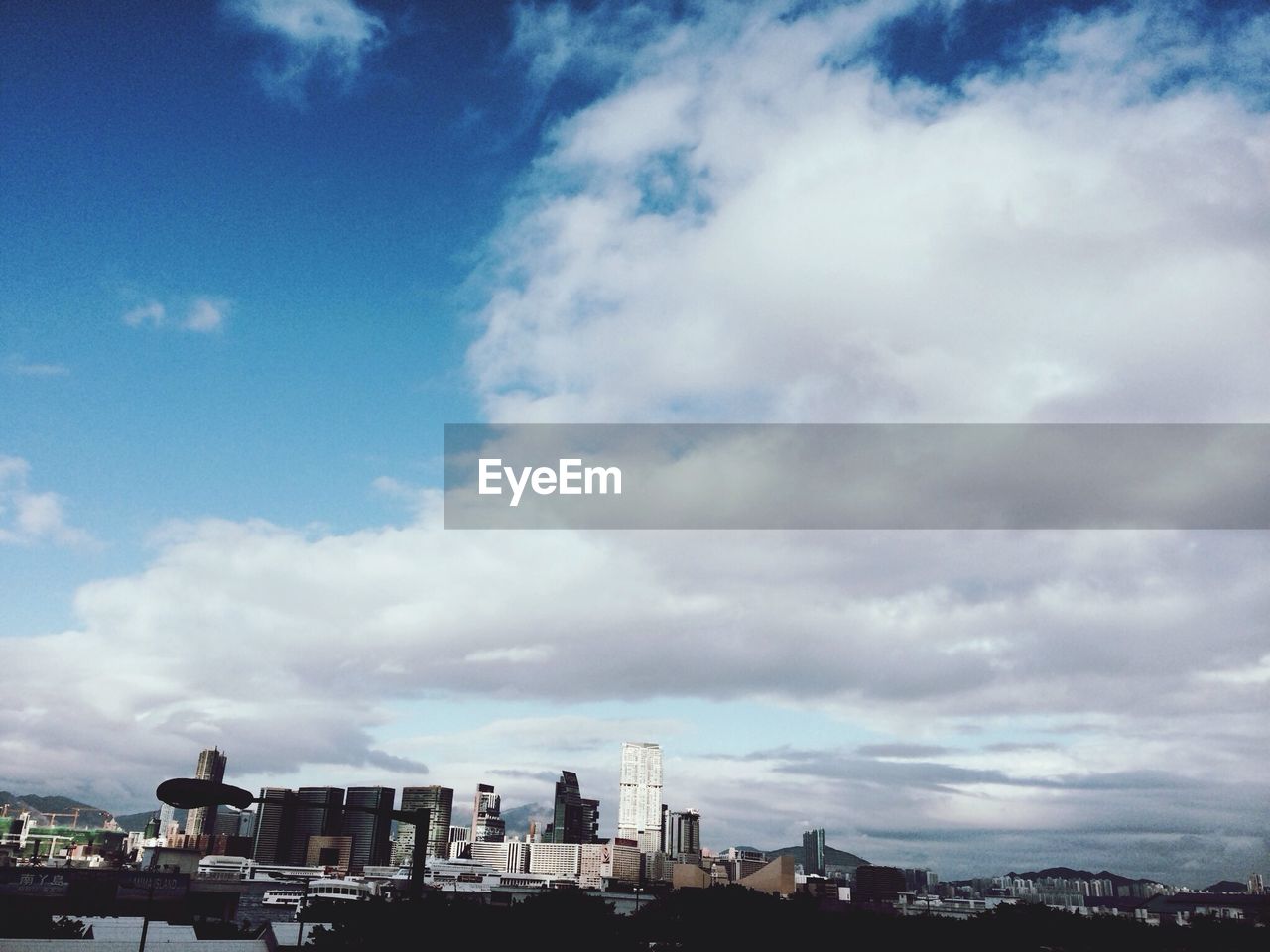 High section of cityscape against blue sky and clouds