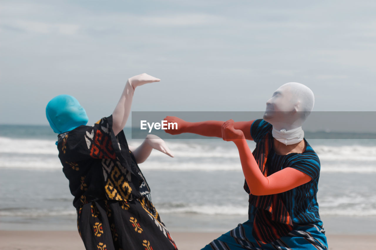 Women standing at beach against sky