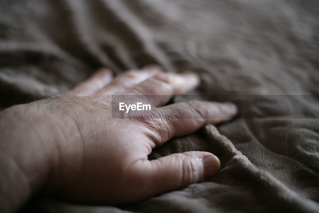 Close-up of hand on bed