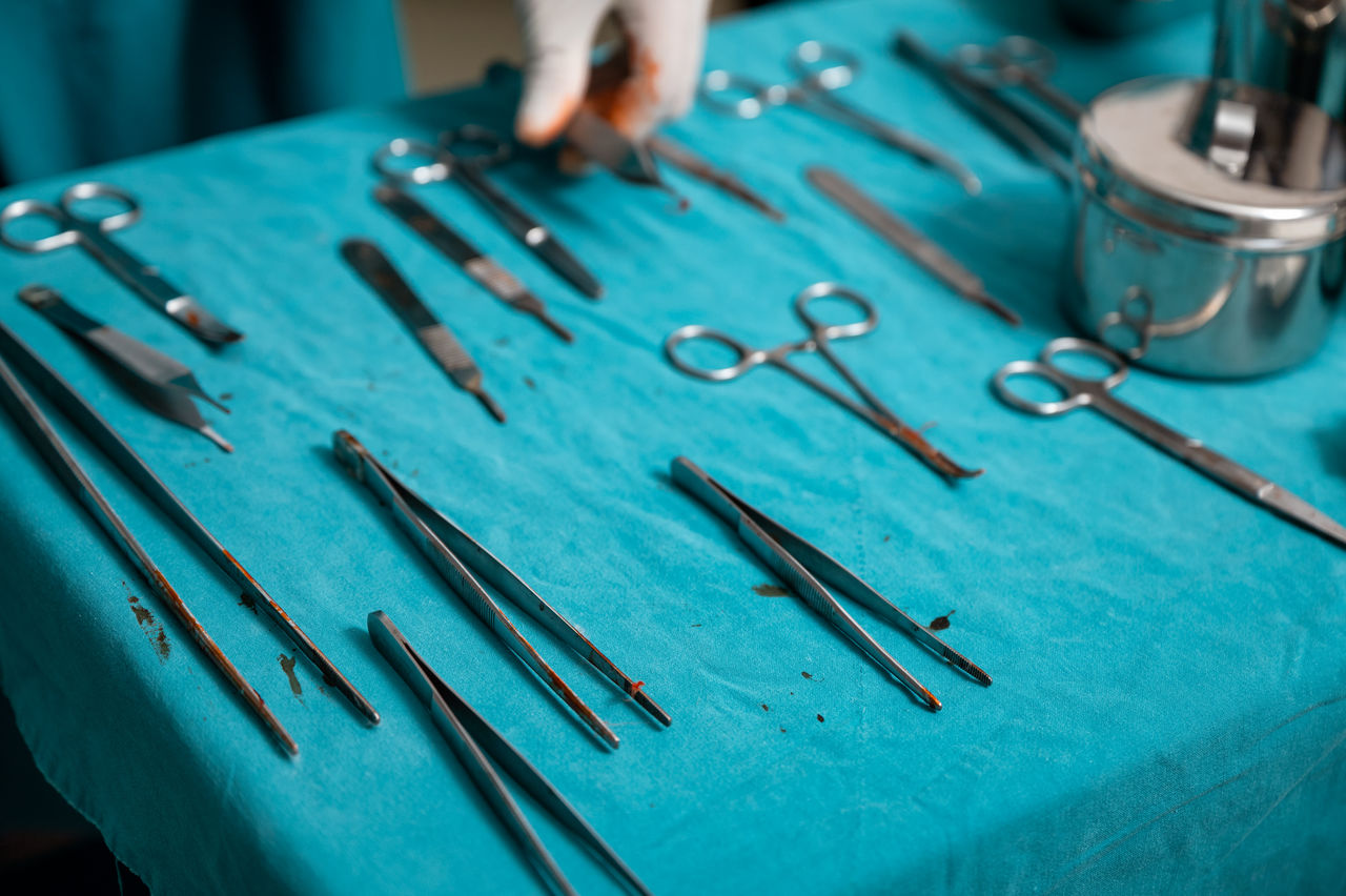 Cropped hand of surgeon holding surgical equipment in operating theater