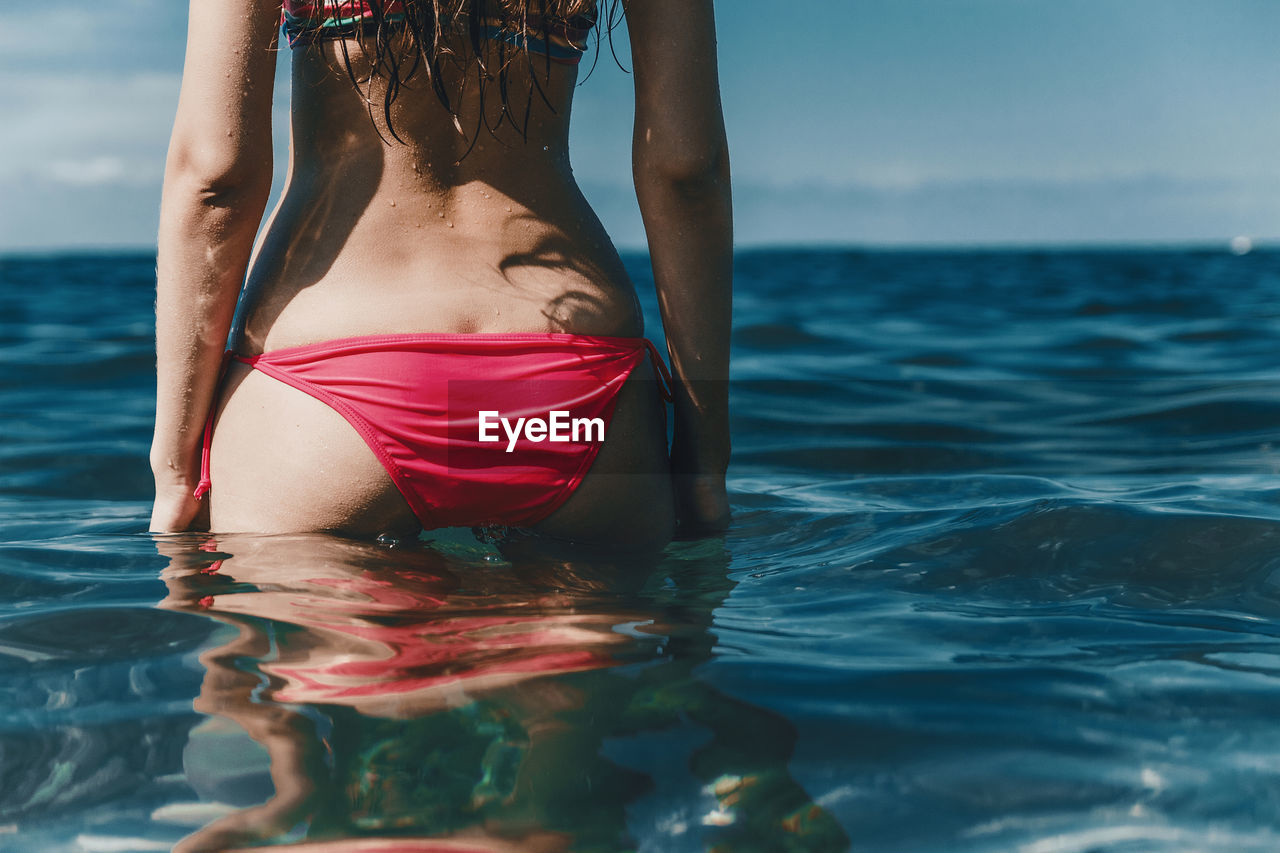 Midsection of sensuous woman wearing red bikini in sea