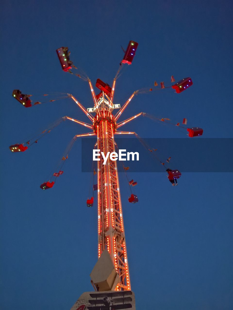 LOW ANGLE VIEW OF ILLUMINATED AMUSEMENT PARK AGAINST SKY