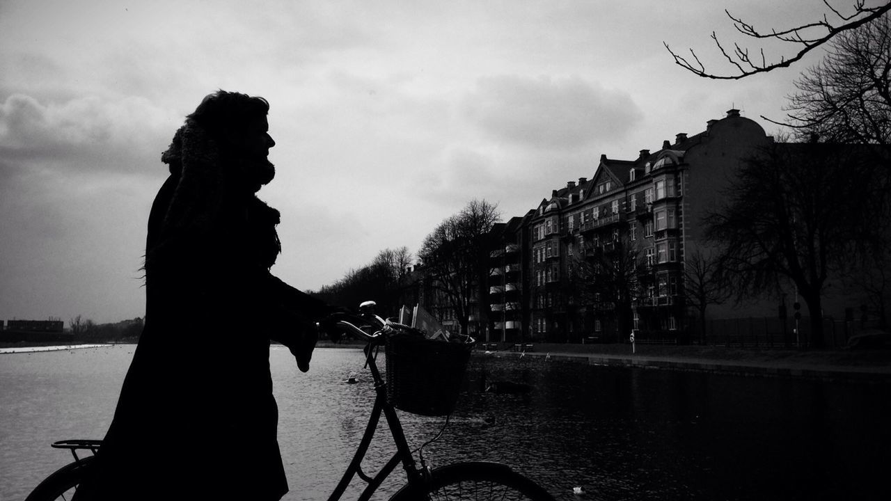 Side view of silhouette person bicycling against the river