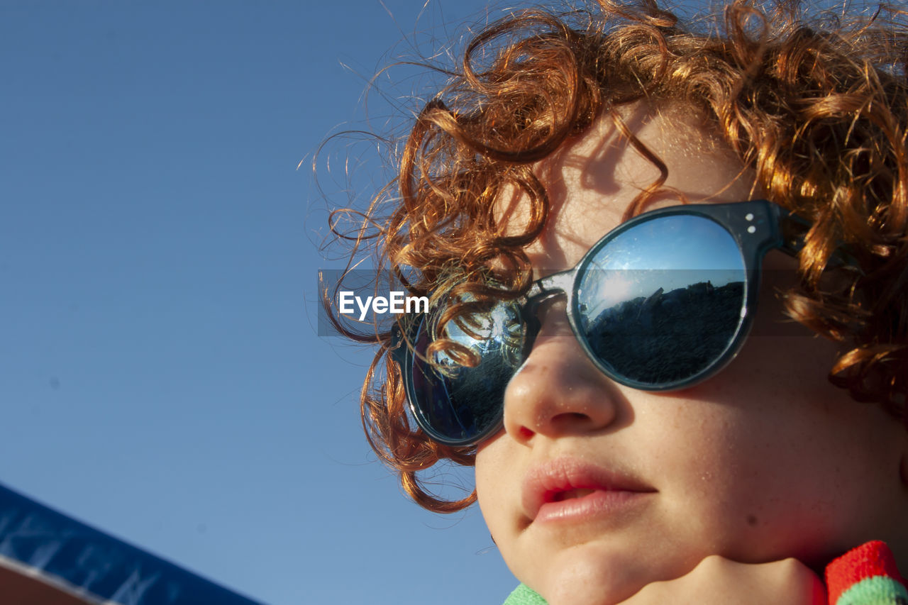 Close-up of girl wearing sunglasses against sky