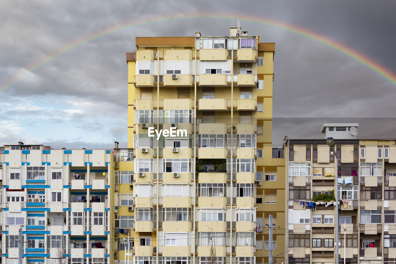 Low angle view of residential buildings against rainbow in sky