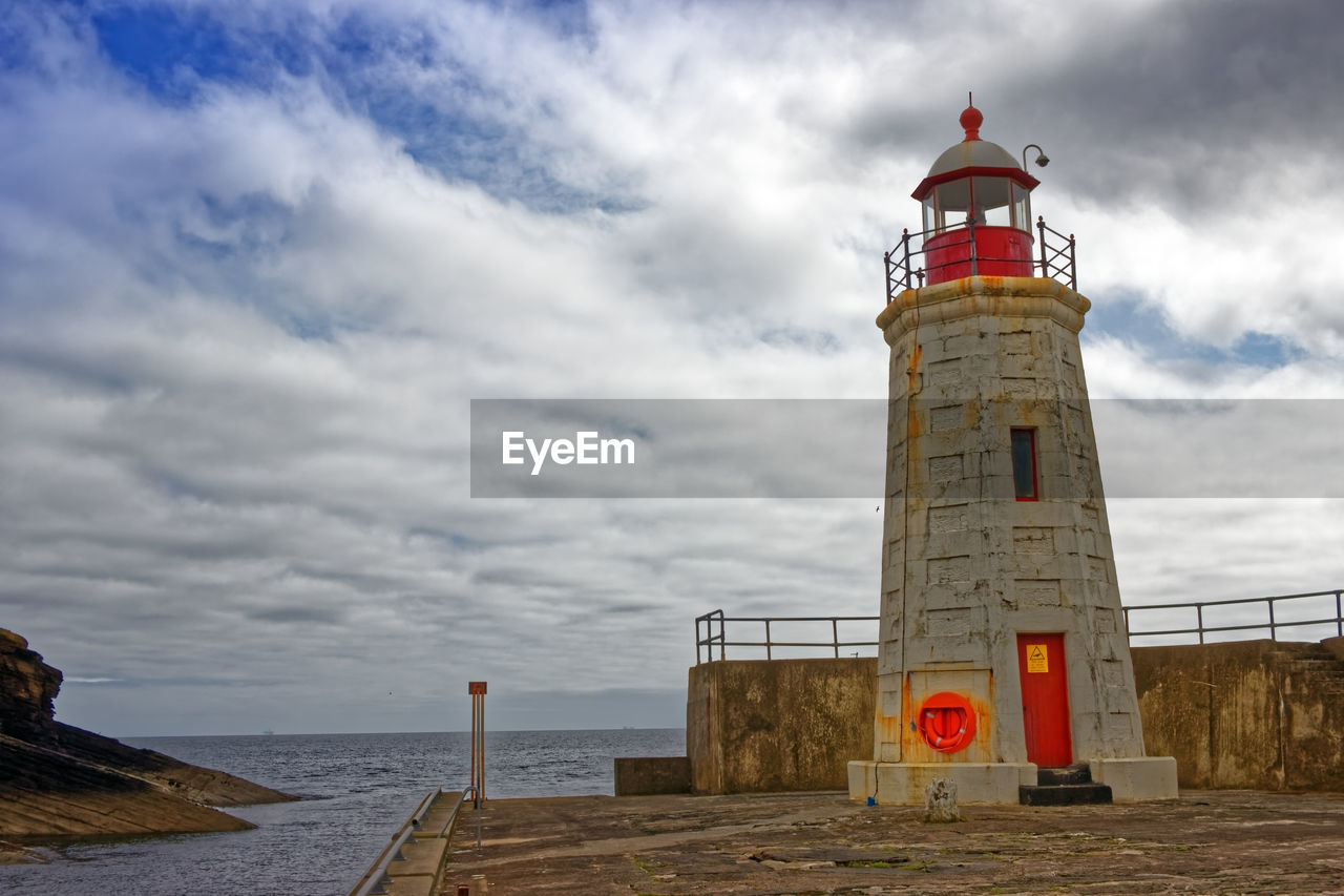 Lighthouse by sea against sky