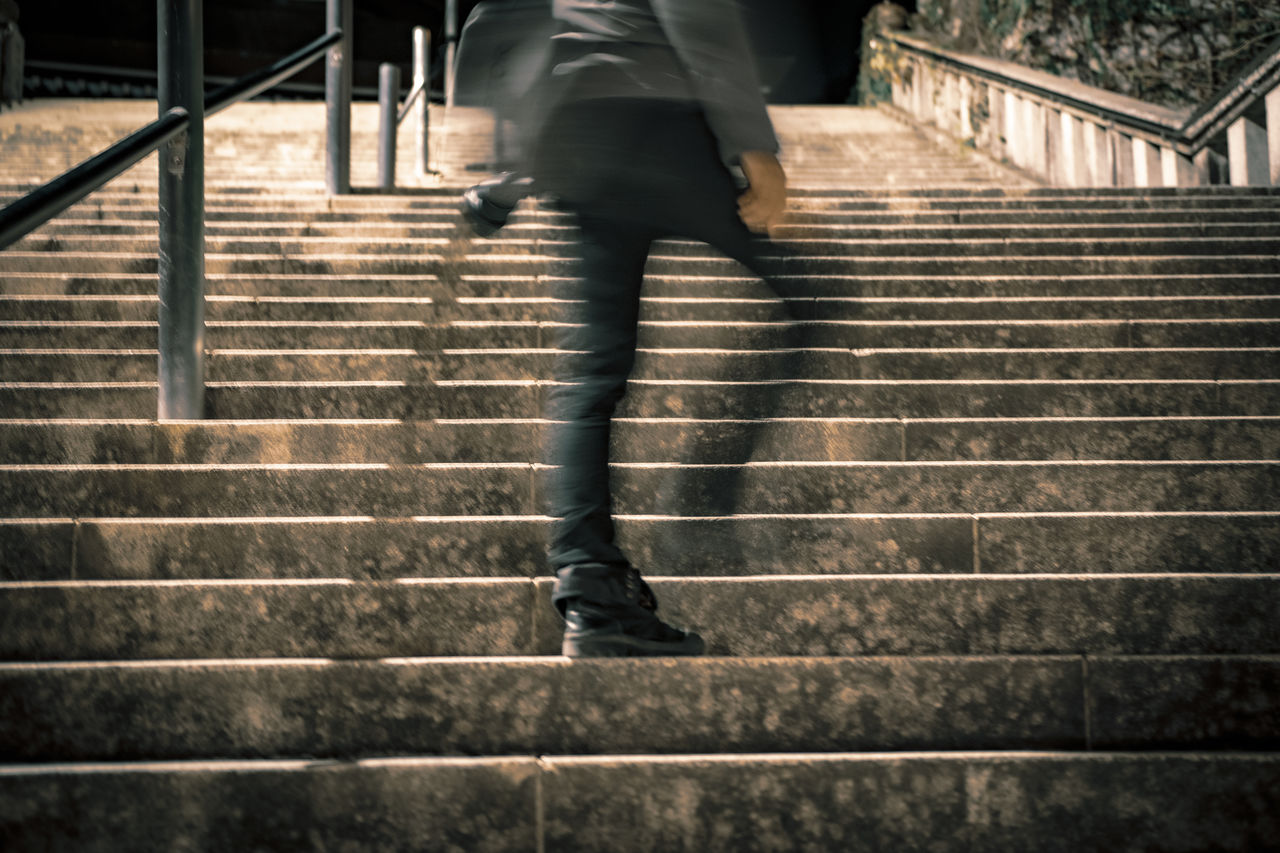LOW SECTION VIEW OF MAN WALKING ON STAIRCASE