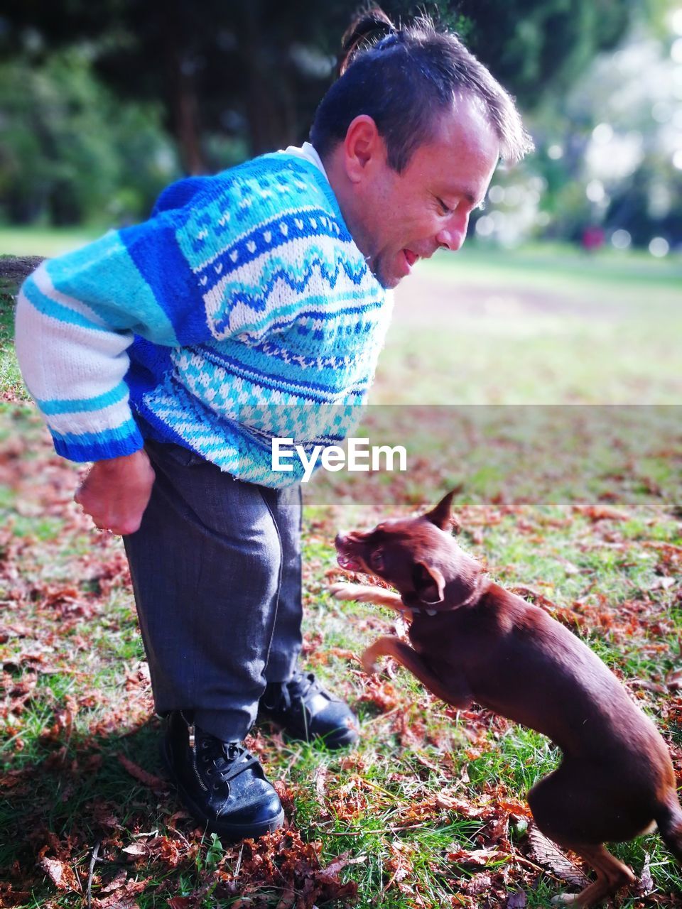 Smiling mature man playing with dog at park