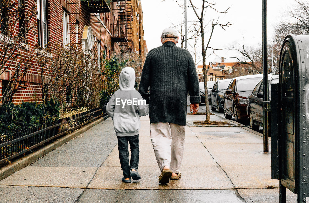 Full length of grandfather with grandson walking on sidewalk