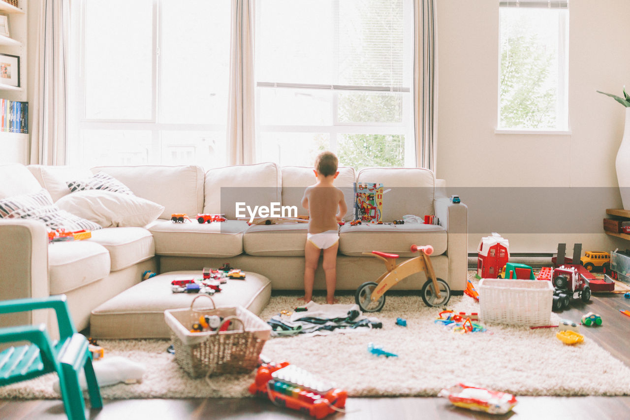 Rear view of boy playing with toys in living room at home