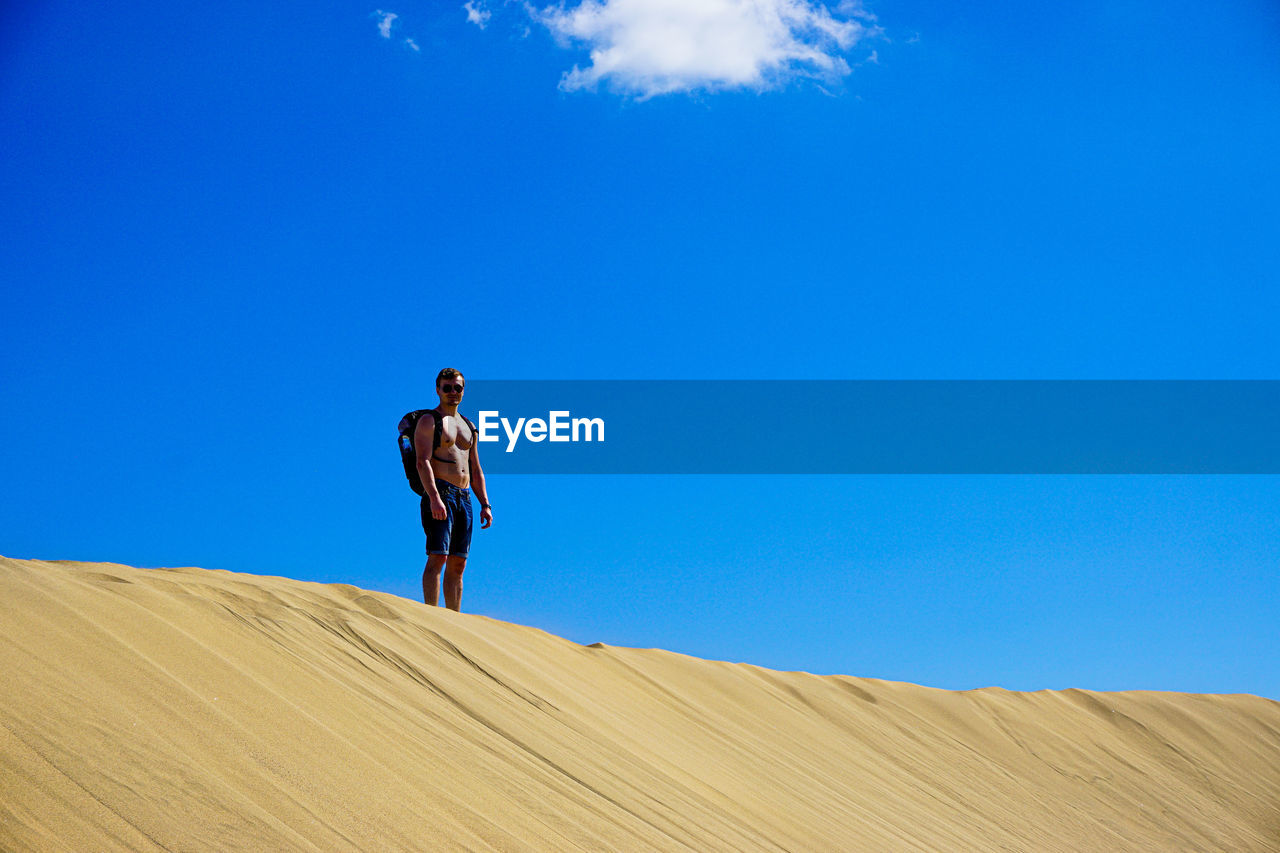 Low angle view of man standing on sand against sky
