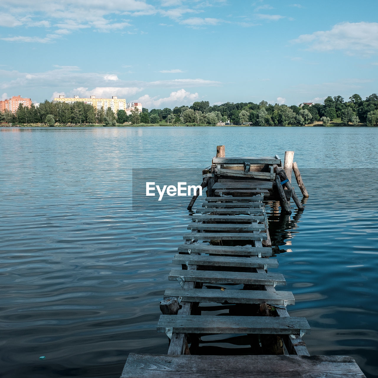 Abandoned wooden pier on lake against sky