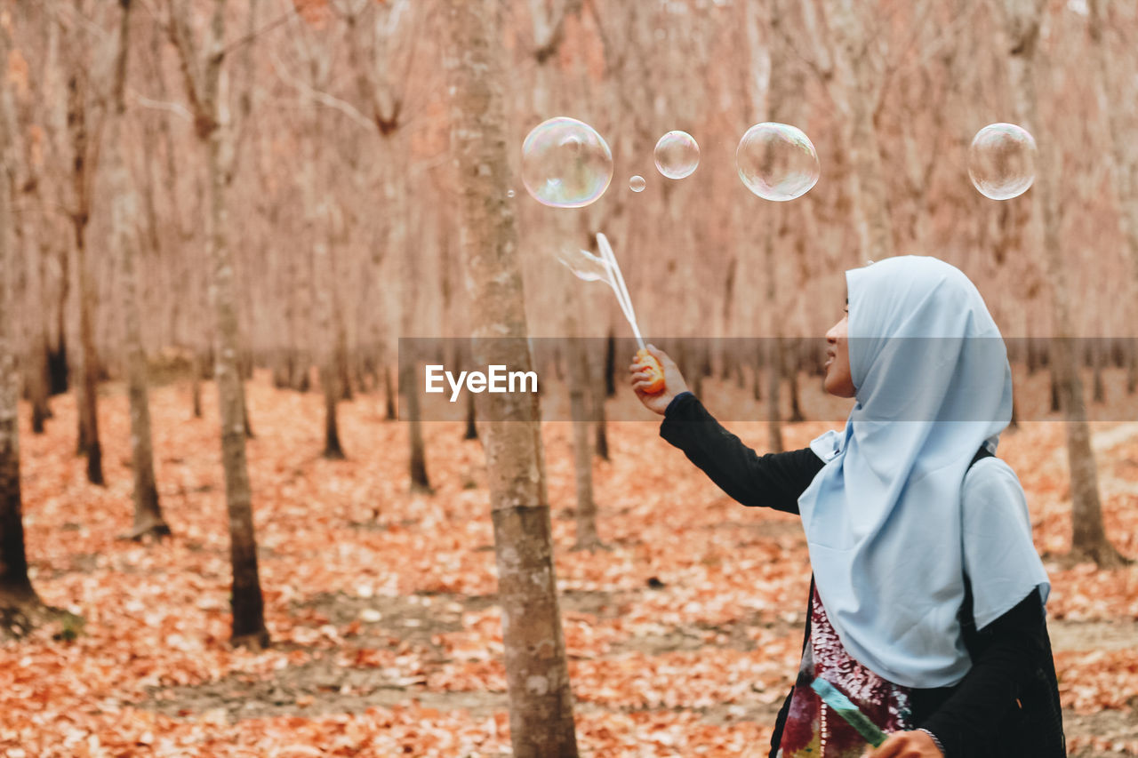 Woman looking at bubbles in forest