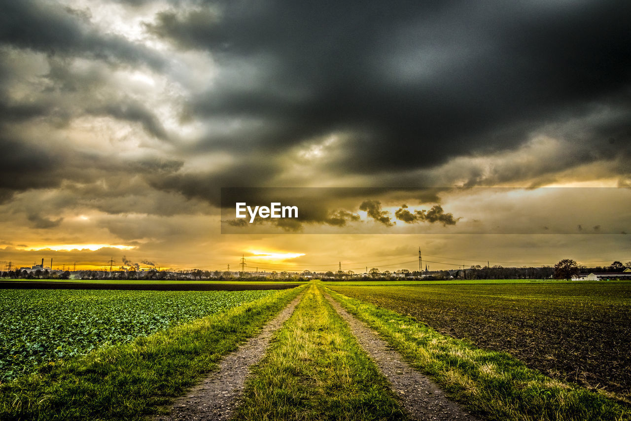 SCENIC VIEW OF AGRICULTURAL FIELD AGAINST DRAMATIC SKY DURING SUNSET