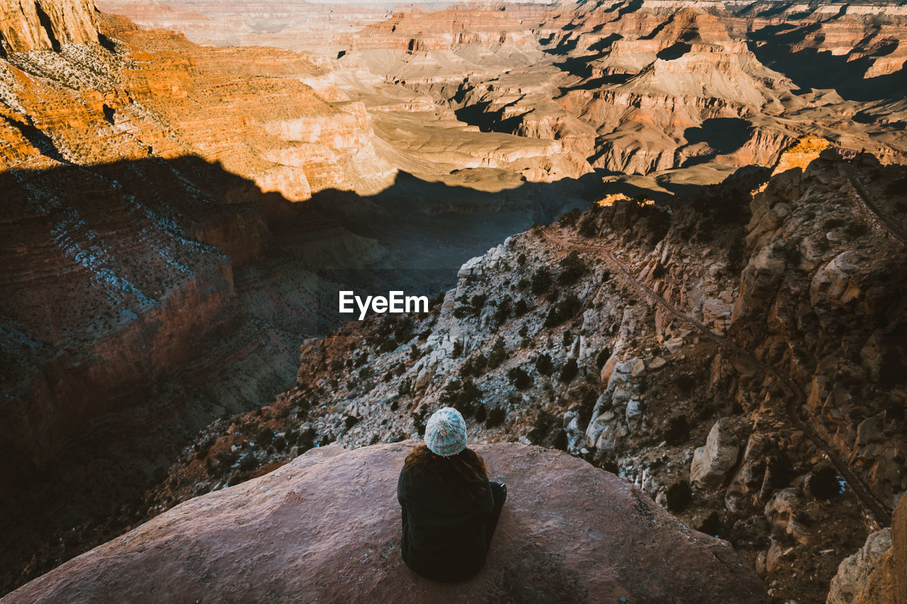 High angle view of woman sitting on cliff at desert