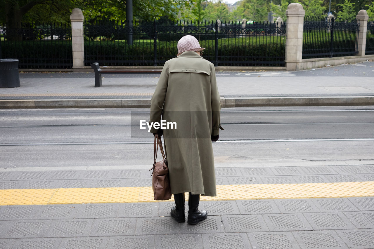 Rear view of old woman waiting for tram