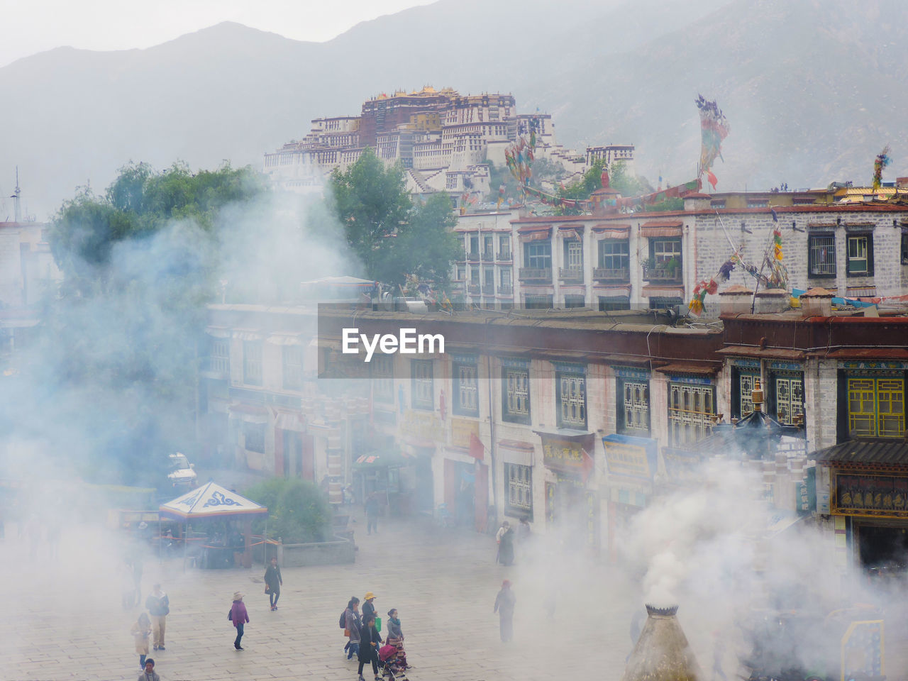 View of barkhor square across the smoke emitted from burners in front of a buddhist temple.