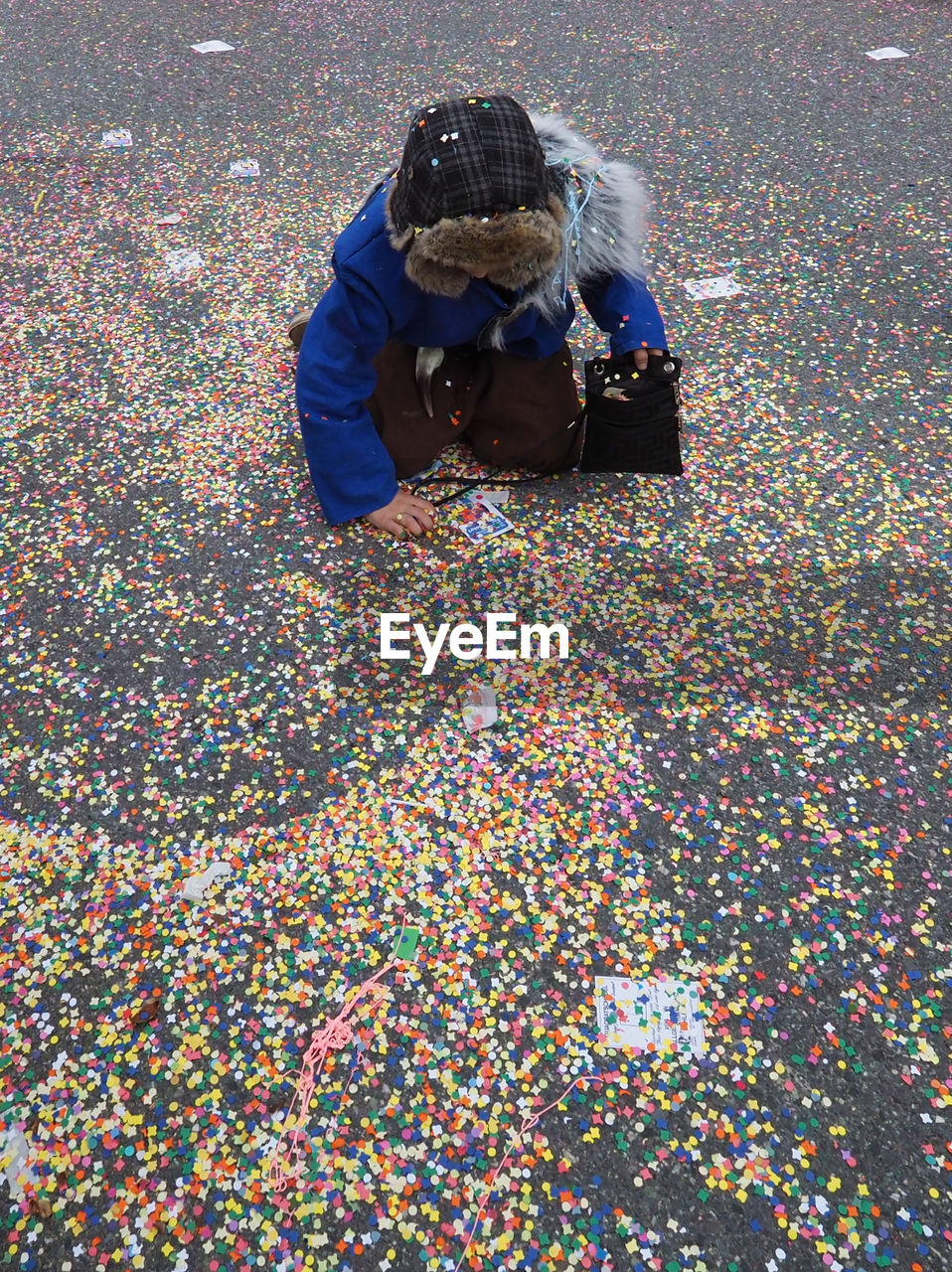 High angle view of person collecting colorful confetti on road