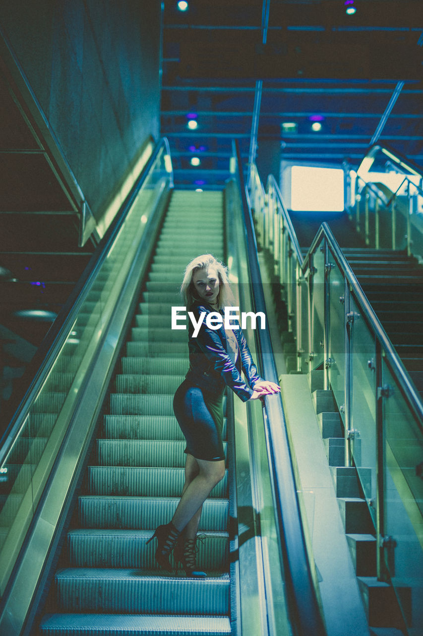 Low angle view of young woman standing on escalator
