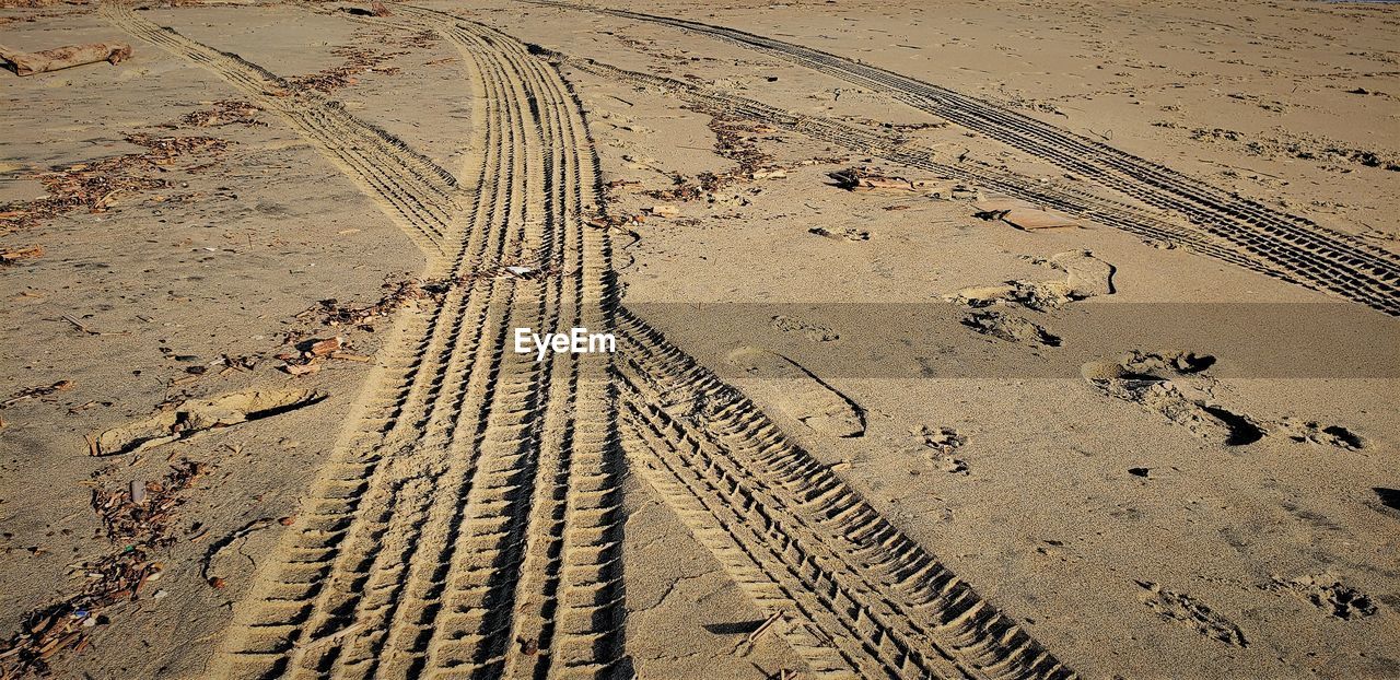 HIGH ANGLE VIEW OF TIRE TRACK ON SAND