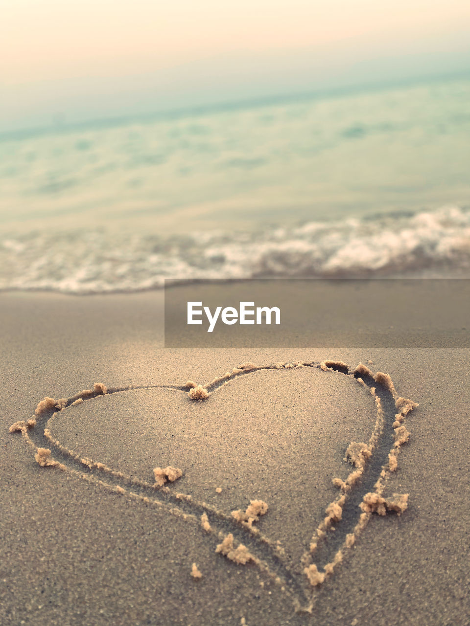 Heart shape on sand at beach against sky