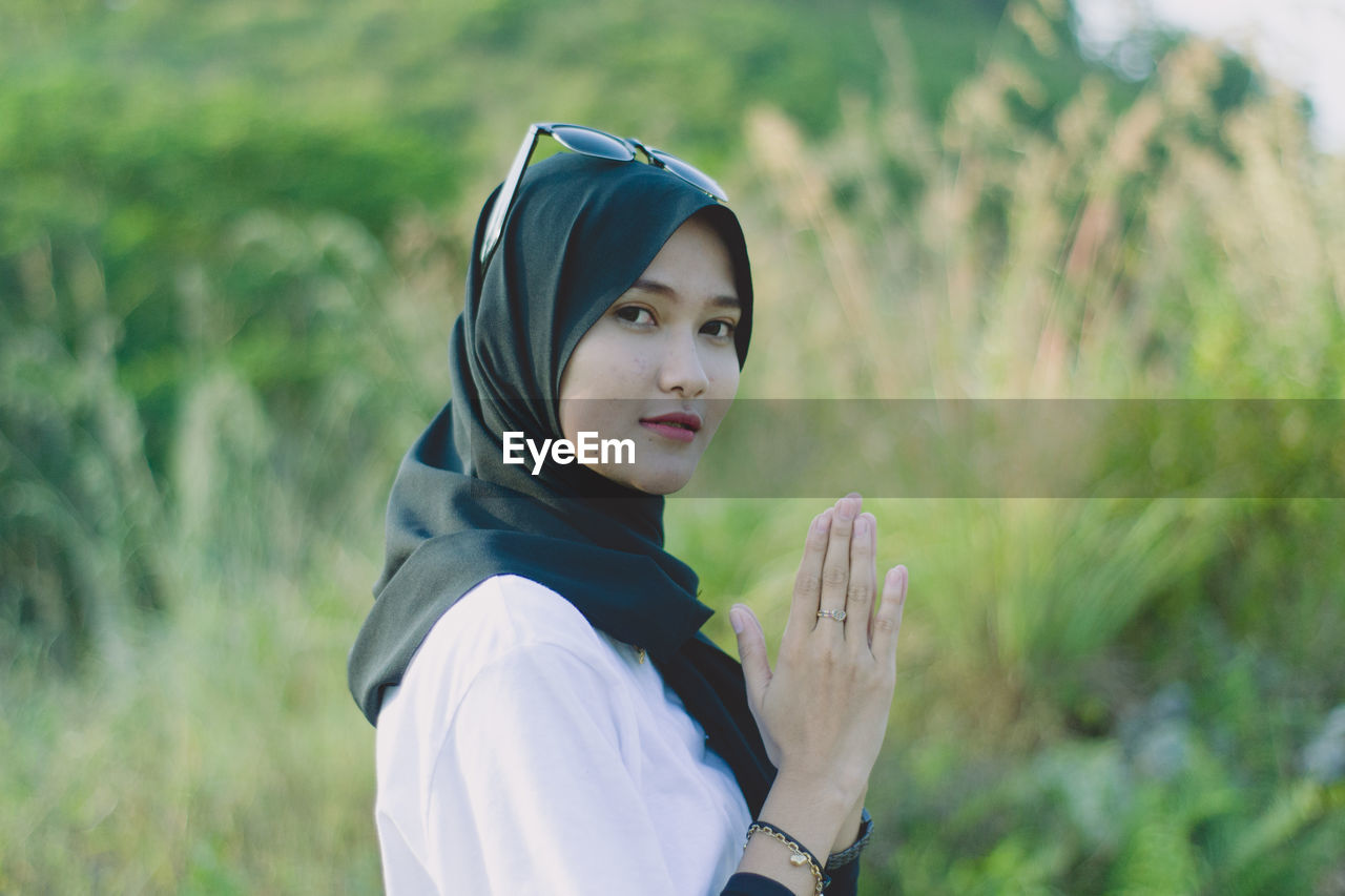 Portrait of young moslem woman pray against plants