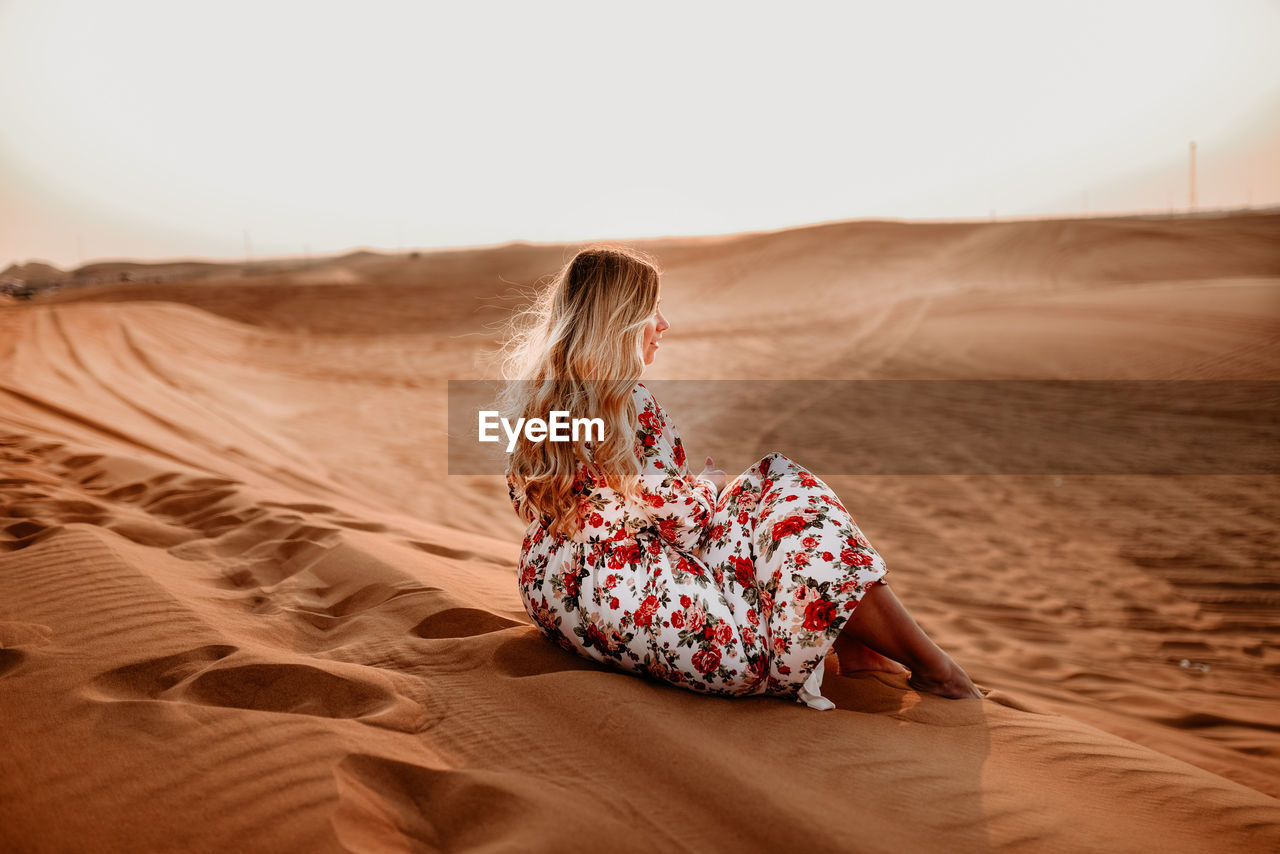  sitting on sand dune in desert. 
