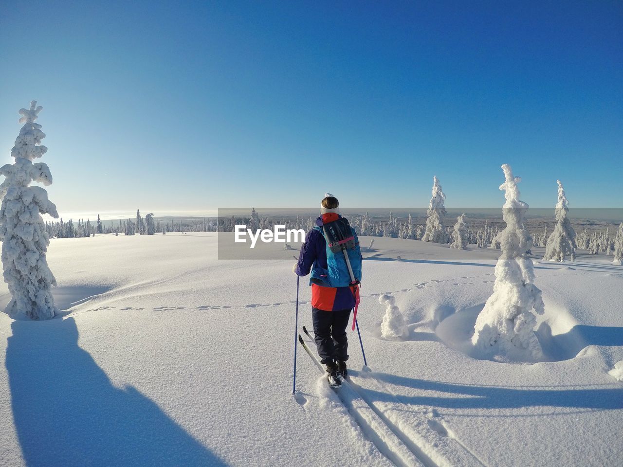 REAR VIEW OF MAN ON SNOWY FIELD AGAINST SKY