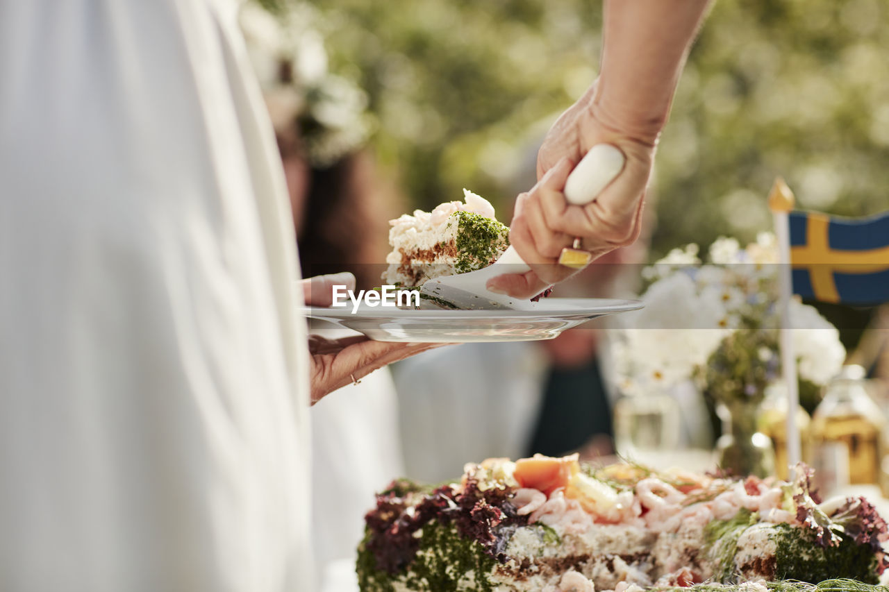 Close-up of woman putting cake on plate