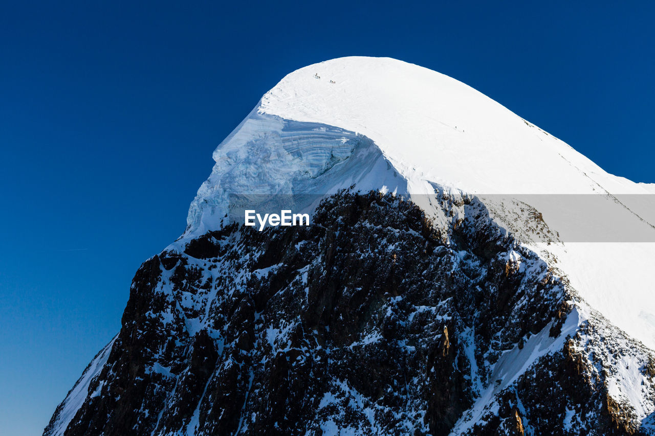 Low angle view of snowcapped mountain against clear blue sky. view from klein matterhorn, swiss alps