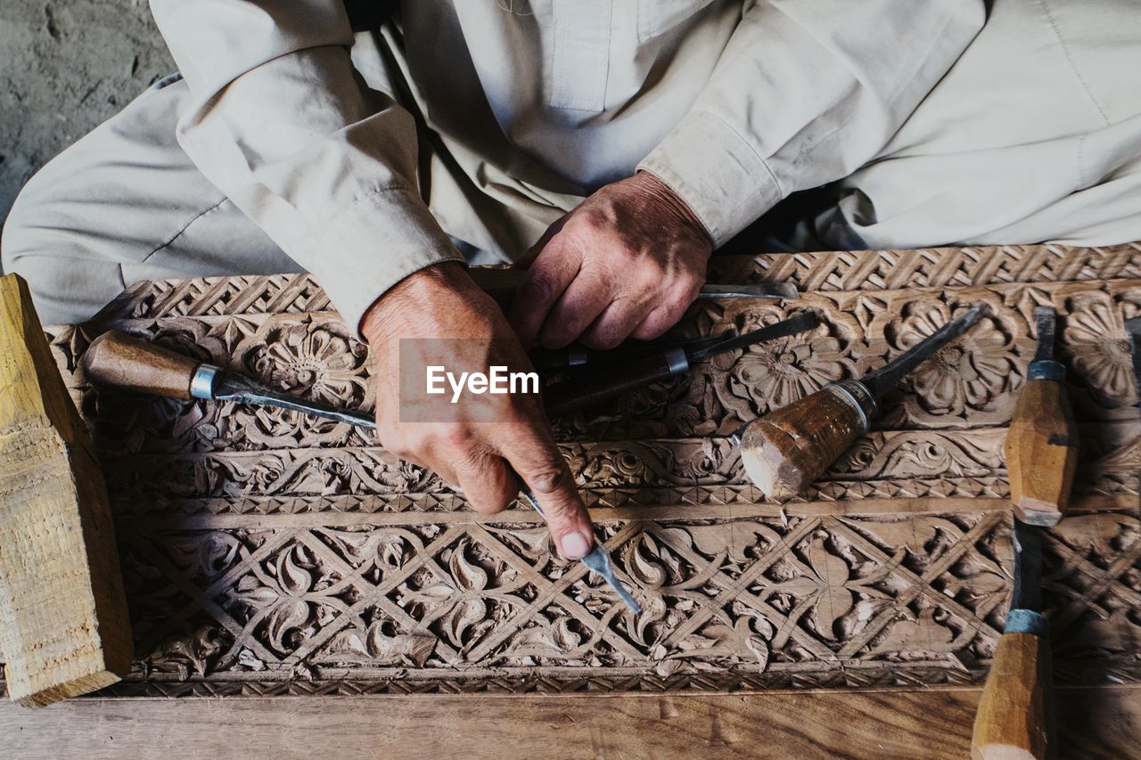 Midsection of man carving wood