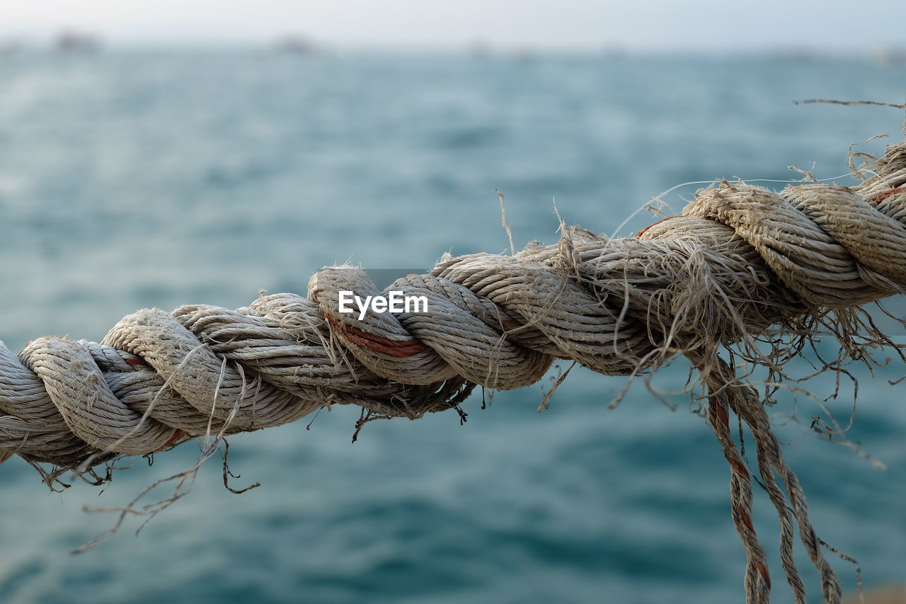Close-up of rope tied to fishing net at harbor